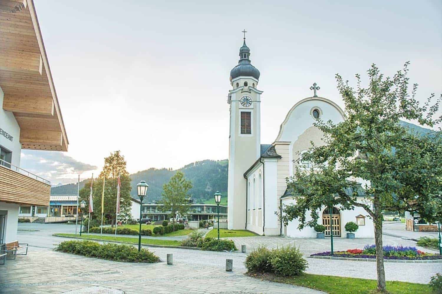 Gemeindeamt mit Dorfplatz und Pfarrkirche im Hintergrund